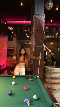 a woman standing next to a pool table