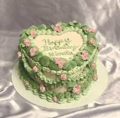 a heart shaped cake with pink flowers on the top and green frosting in the middle