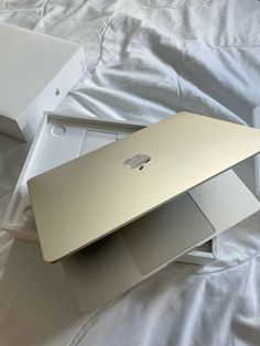 an apple laptop sitting on top of a white sheet