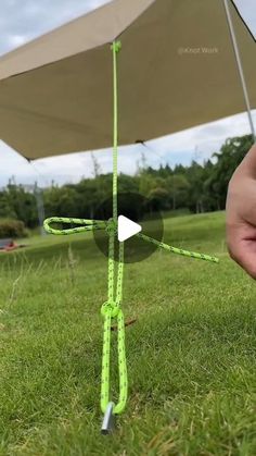 someone holding an umbrella in the grass with their thumb on it's handle and string