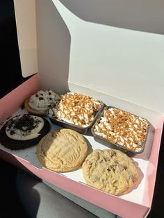 an open box filled with assorted cookies and pastries on top of a table