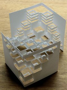 a paper model of a building on a wooden table with one section cut out and the other part folded up