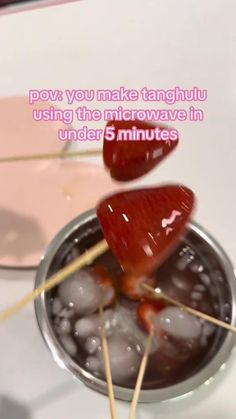 two strawberries on skewers in a metal bowl with ice cubes and toothpicks