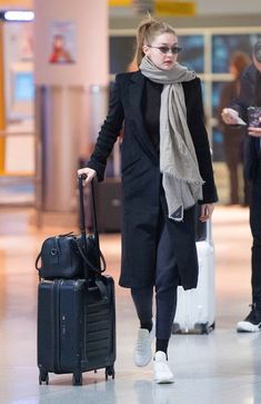 a woman walking through an airport with her luggage