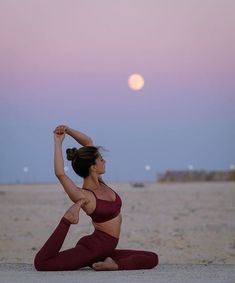 a woman is doing yoga on the beach