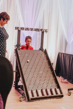 a woman standing in front of a large metal object on top of a wooden floor