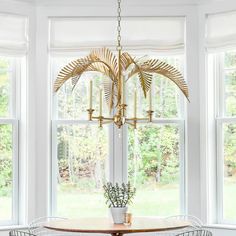 a dining room table with four chairs and a chandelier hanging from the ceiling