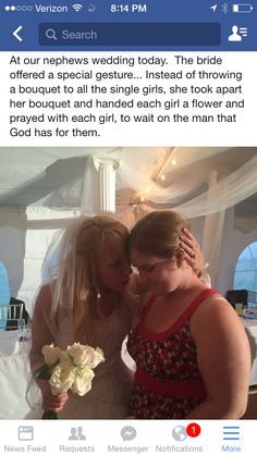 two women are kissing each other in front of a bed with white flowers on it