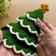 a crocheted christmas tree ornament being held by someone's hand