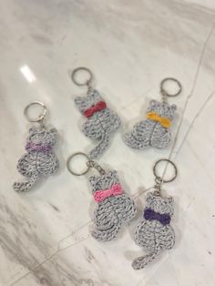 crocheted keychains with teddy bears on them sitting on a marble surface