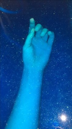 a person's hand with blue powder on it and stars in the sky above