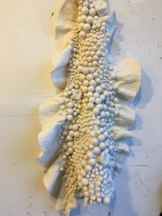 a sculpture made out of white rocks on a wall in the shape of a flower