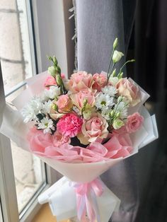 a bouquet of pink and white flowers in front of a window