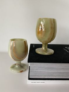 two glass goblets sitting on top of a book next to it's cover