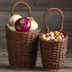 two wicker baskets filled with vegetables sitting on top of a wooden table next to each other