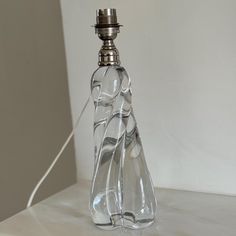 an empty glass bottle sitting on top of a white counter next to a light bulb