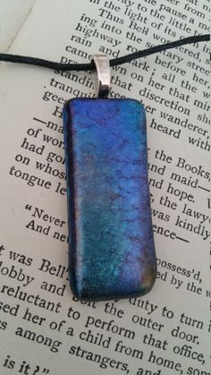 a blue rectangular pendant sitting on top of an open book