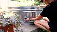 a woman is sitting on the ground next to a potted plant and water fountain