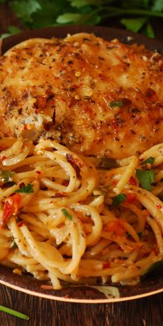 a plate of pasta with chicken and parmesan cheese on the side, garnished with fresh herbs