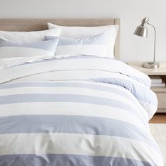 a bed with blue and white striped comforter in a bedroom next to a night stand