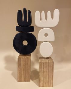 two sculptures made out of wood, one with black and white designs on it's sides