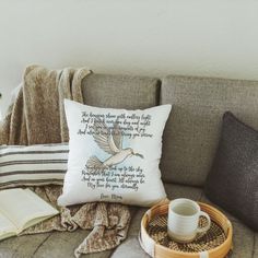 a coffee cup sitting on top of a couch next to an open book and a basket