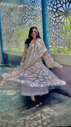 a woman in a white dress is standing on the ground with her arms spread out