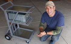 a man kneeling down next to a cart filled with metal items and smiling at the camera