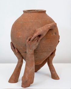 an old clay pot with two hands on it