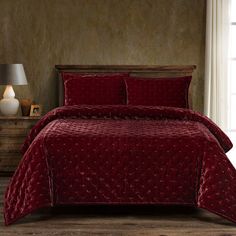 a bed with red comforter and pillows in a room