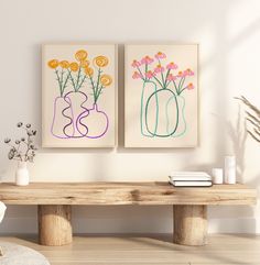 two vases with flowers sit on a table in front of a wall mounted art piece