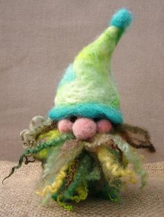 a small green and yellow gnome's hat on top of a piece of cloth