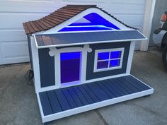 a small house with blue lights on it's roof and side windows in front of a garage