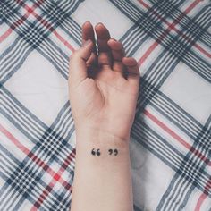 a woman's wrist with two small black hearts on the left side of her arm