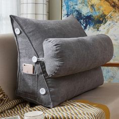 two gray pillows with buttons on them sitting next to a coffee cup and phone holder