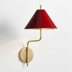 a red and gold wall light with a red shade on the lamp is next to a white wall