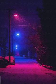 a street light that is lit up in the dark with red lights on it and snow all around