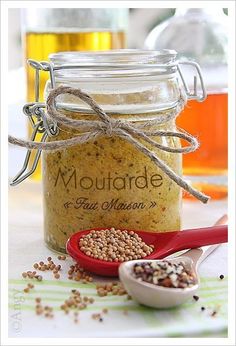 a jar filled with lots of mustard next to a spoon and some other items on a table