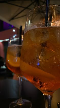 two glasses filled with liquid and ice sitting on a table