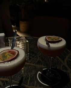 two cocktails sitting on top of a table next to each other in coupe glasses