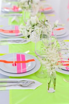 the table is set with plates, silverware and flowers in vases on it