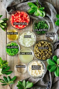 the ingredients for an italian salad laid out in bowls on a wooden table with green leaves