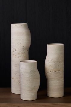 three white vases sitting on top of a wooden table