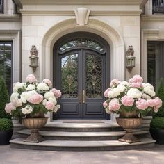 two large vases filled with pink and white flowers sit on the front steps of a house