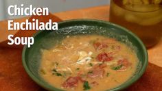 chicken enchilada soup in a green bowl on a cutting board next to bread