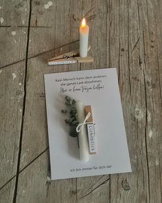 a note with a candle on top of it next to a small piece of paper