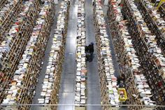 two people are walking among rows of books