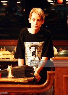 a young boy sitting at a table in front of a wooden cabinet with chess pieces on it