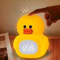 a yellow ducky alarm clock sitting on top of a wooden table