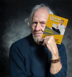 an older man is holding up a book